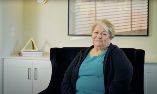 a woman sitting in a chair wearing a blue blouse